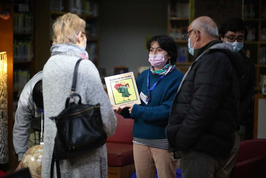 Fotografía en Biblioteca del Campus Villarrica. Jefa de Biblioteca muestra un libro infantil a asistentes. 