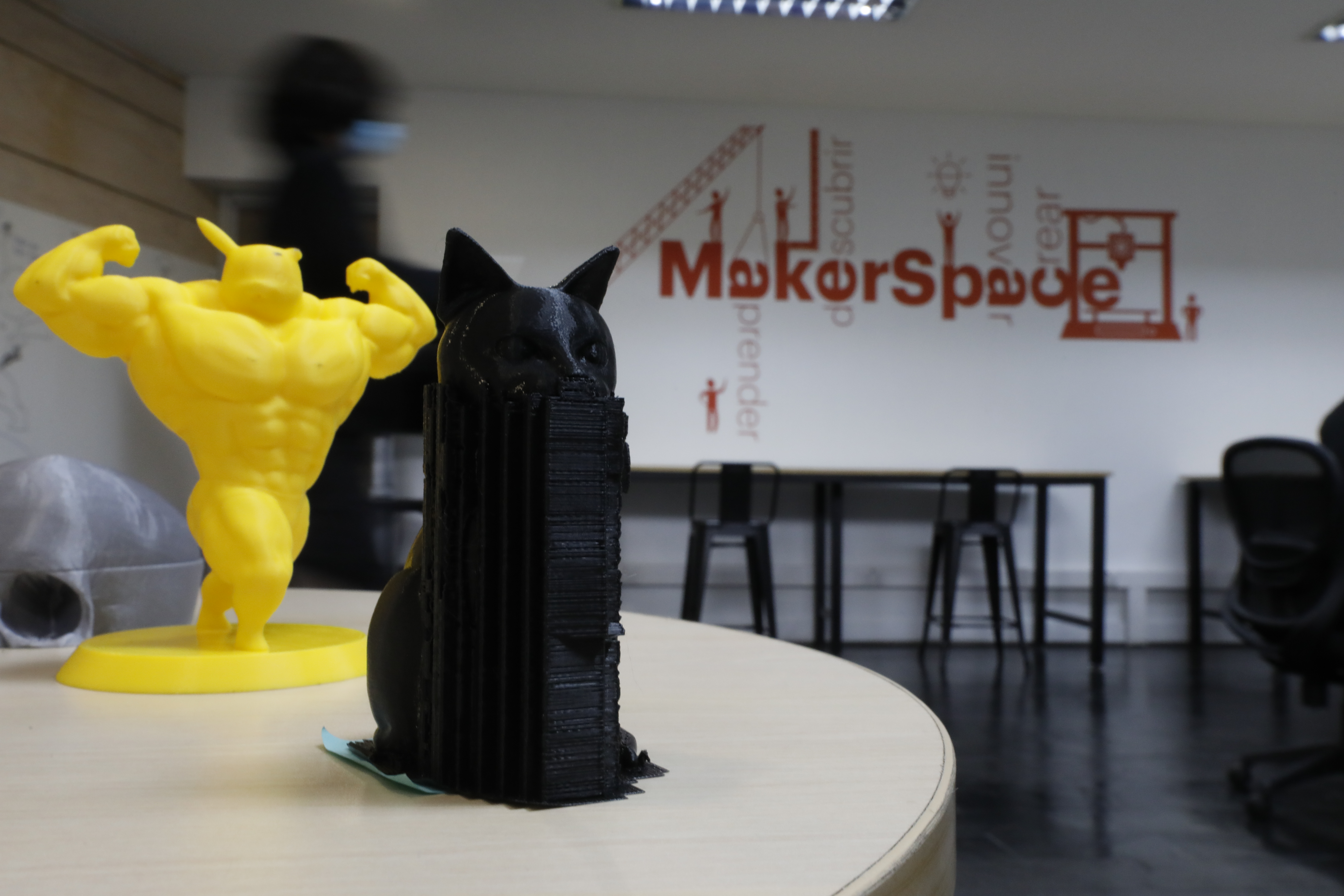 Foto del makerspace. Se ven figuras hechas con las impresoras 3D como un personaje musculoso amarillo y un gato, entre otros.