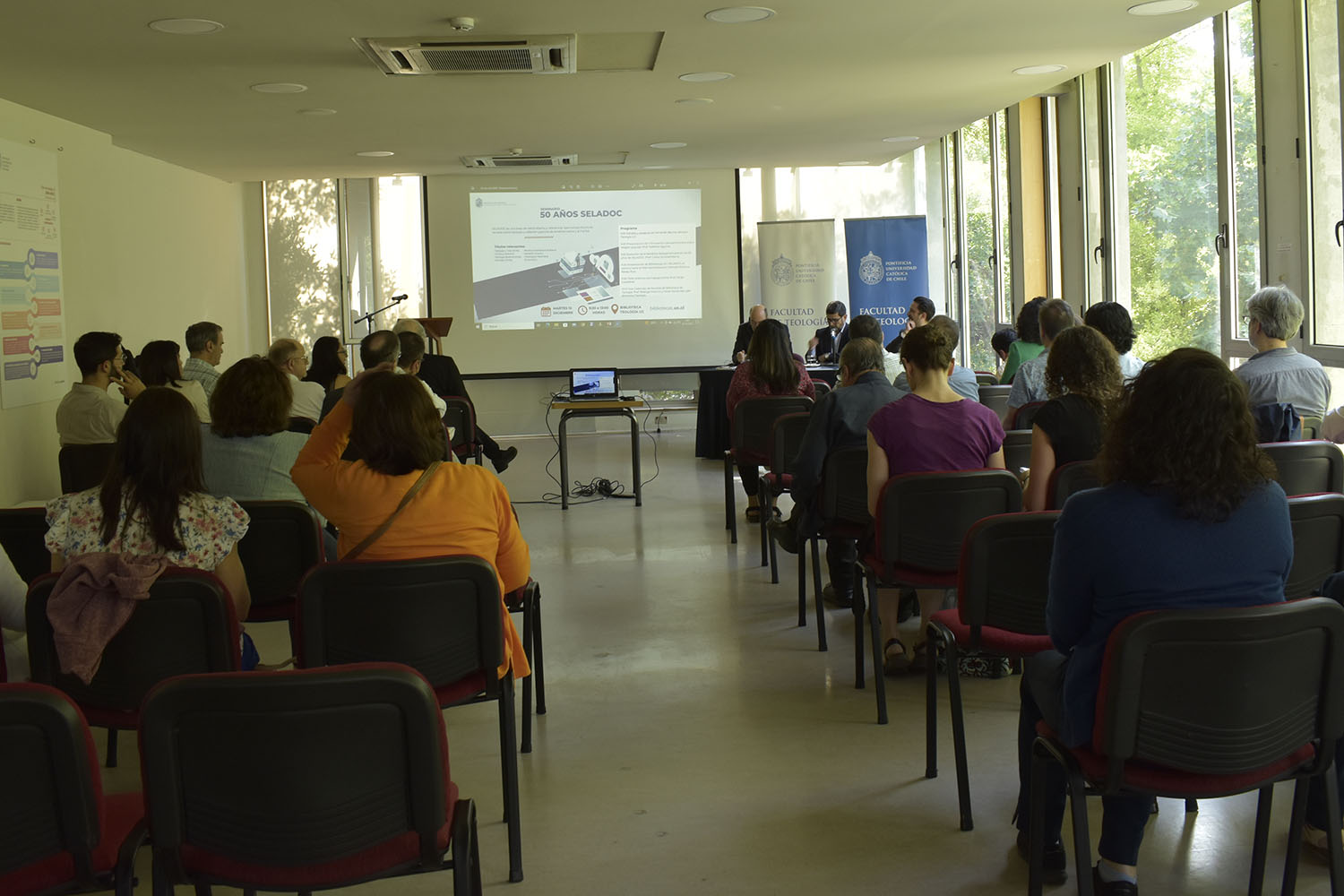 Fotografía del seminario 50 años de SELEDOC. La imagen muestra a los asistentes a la actividad mirando la presentaciones.