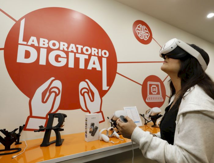 Fotografía de una estudiante usando gafas de realidad virtual en el laboratorio digital.